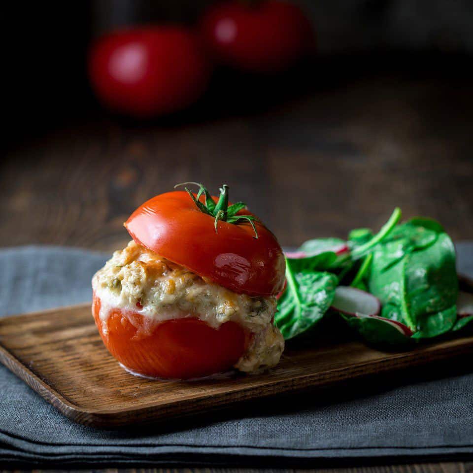 side shot of a halved tomato with tuna salad and melted cheese