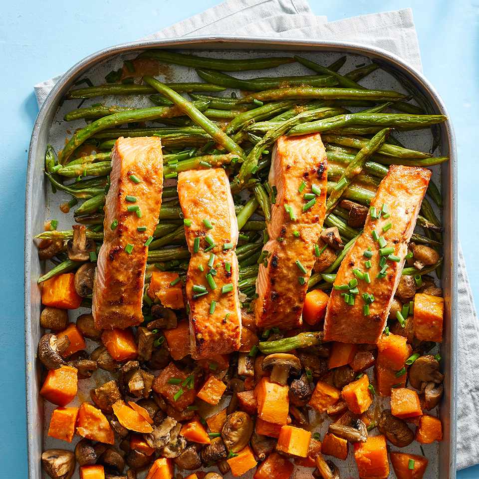 sheet pan of salmon and vegetables on blue background