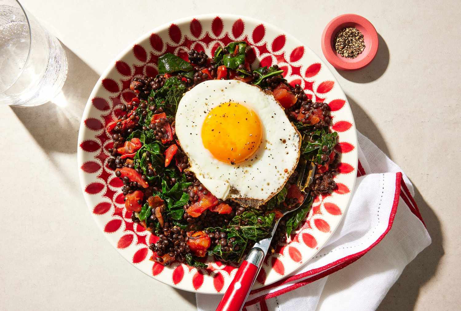 braised lentils kale and egg in a bowl with a fork