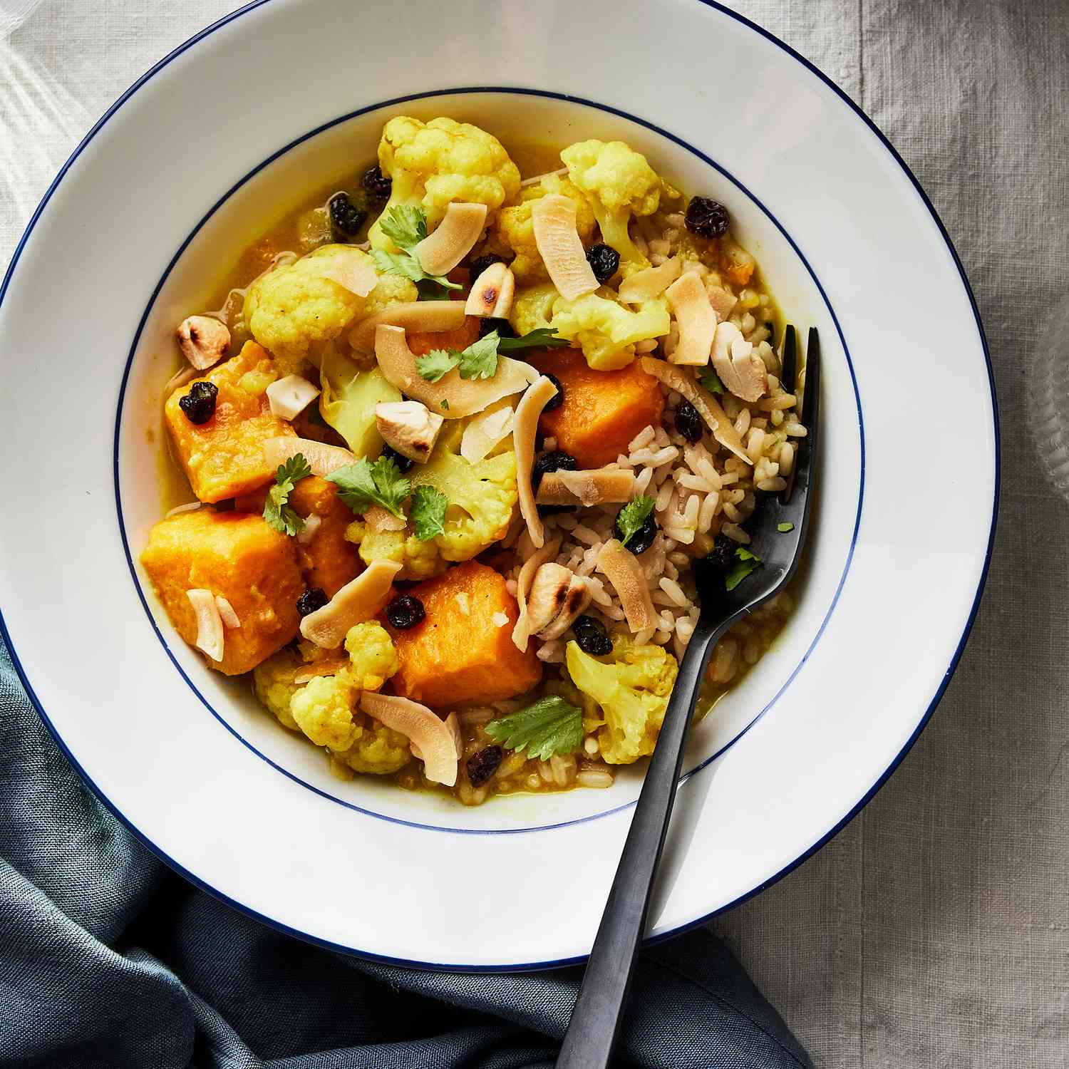 a recipe photo of the Slow-Cooker Curried Sweet Potato & Cauliflower with Coconut & Cashews served in a bowl