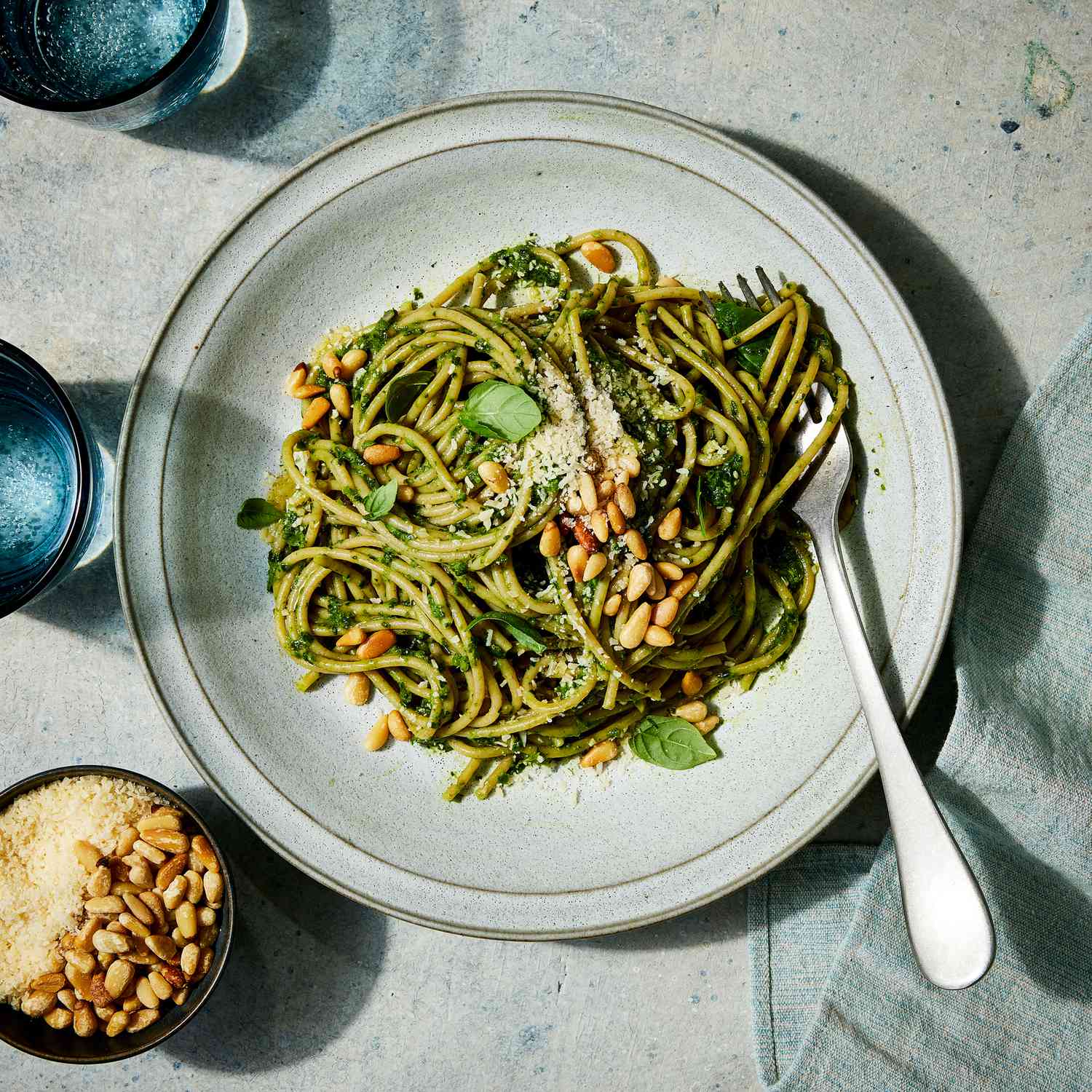 a recipe photo of the Super Green Pasta served on a plate and topped with pine nuts and cheese