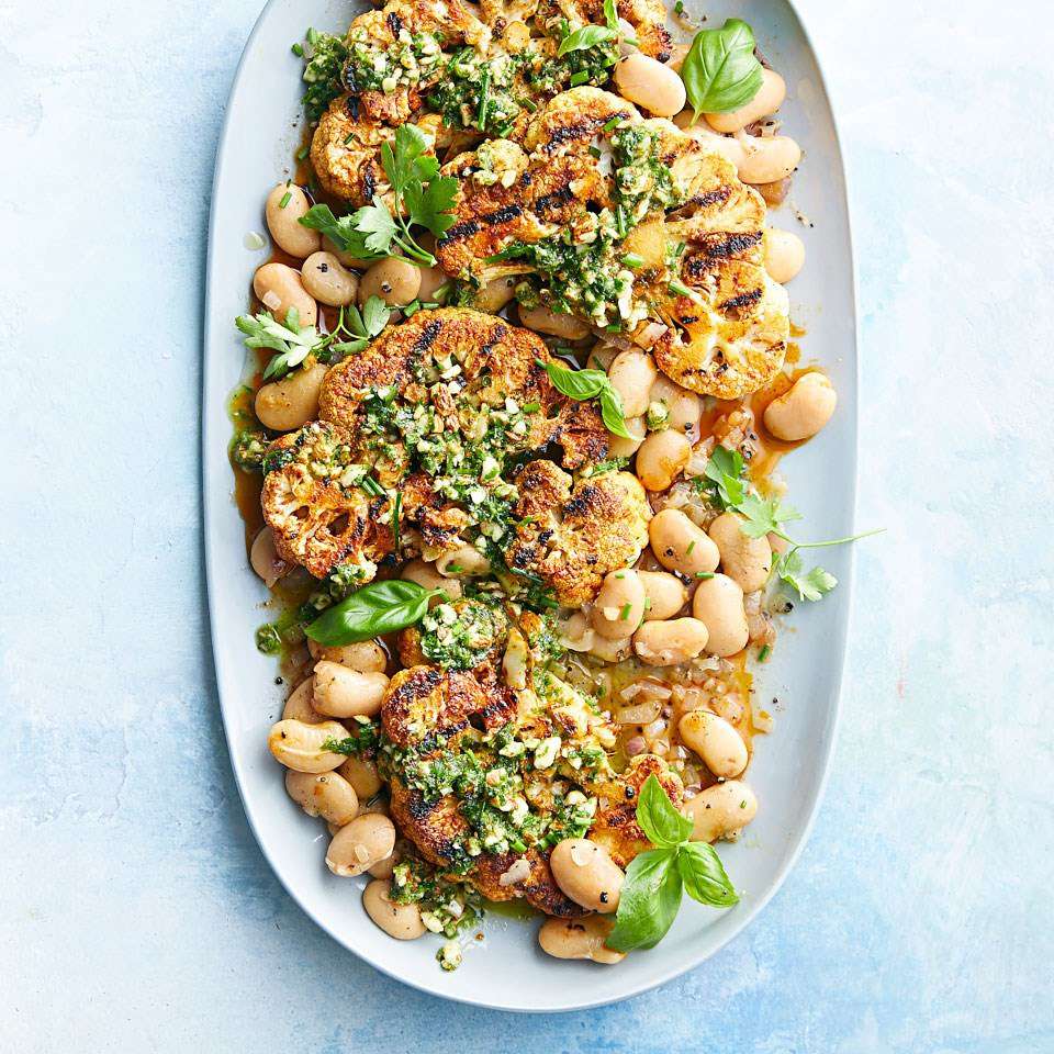 grilled cauliflower steaks with almond pesto & butter beans on a platter