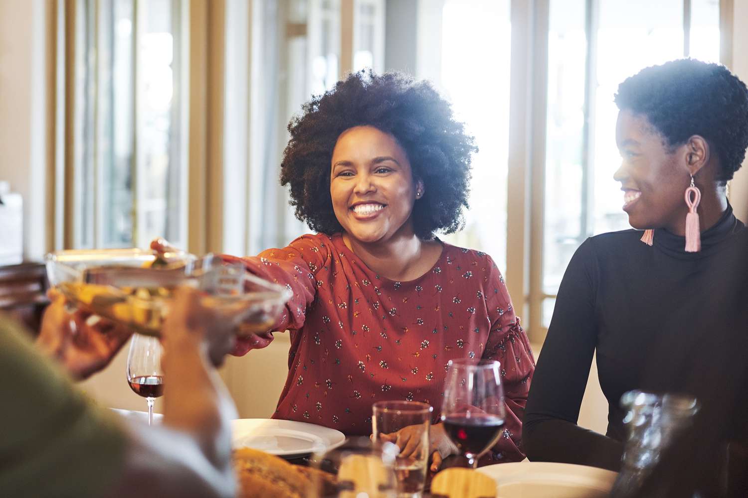 a photo of a woman getting passed a dish of food at thanksgiving dinner